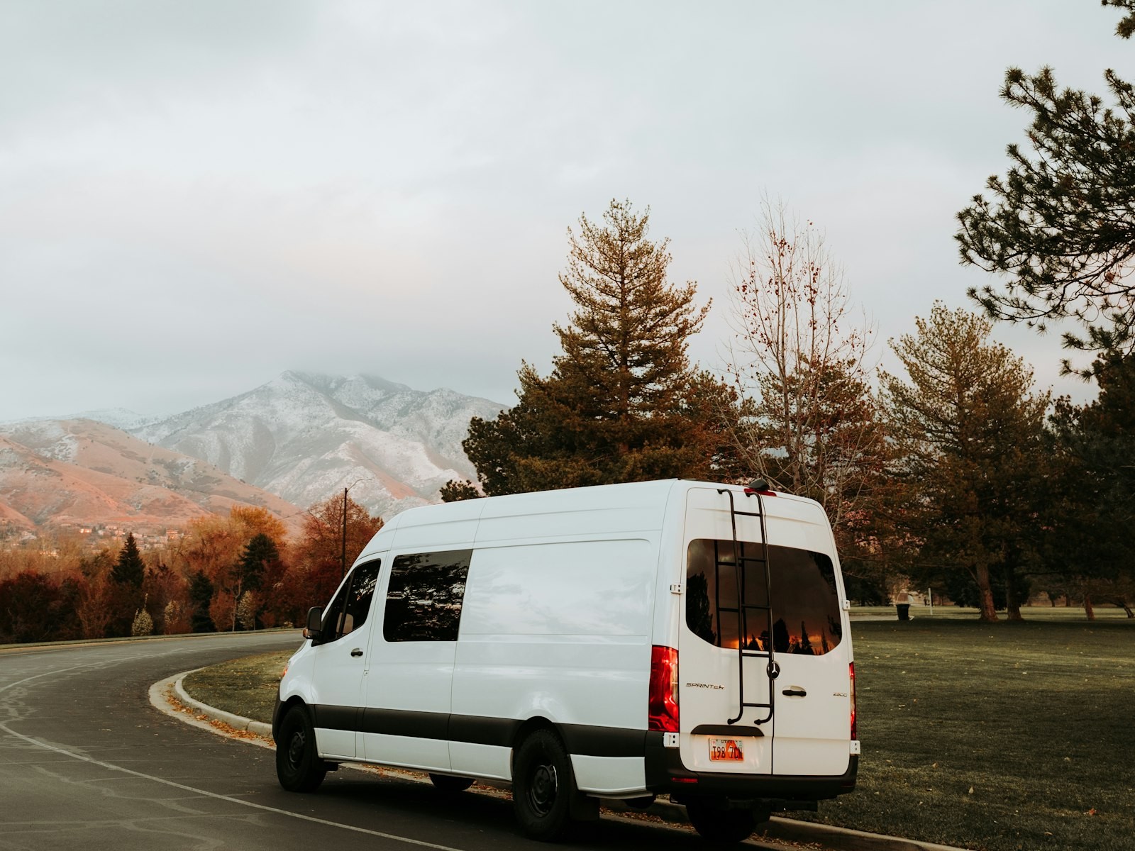 Van Sprinter blanca en carretera hacia Ollantaytambo, con montañas de fondo